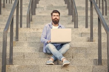 bearded freelancer man has online laptop communication outdoor. freelancer man has online laptop communication outside. freelancer man has online laptop communication in the street. freelancer man