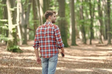back view of walking man walk outside. walking man wearing checkered shirt for a walk. photo of walking man walk in the forest. walking man walk outdoor.