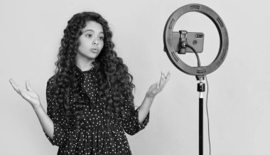 Uzun kıvırcık saçlı hayret bir çocuk blog için video yapıyor..