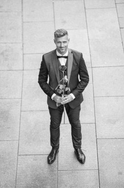 Smokinli şık bir adam. Dışarıda papyon giyen bir adam. Kırmızı güllü yakışıklı smokinli adam..