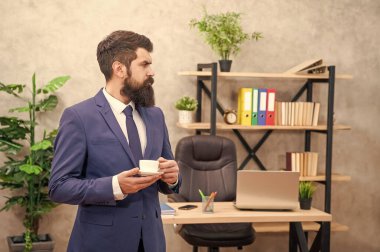 Ciddi sakallı iş adamı ofiste fotokopi alanı ve iş yeri olan kahve içiyor..