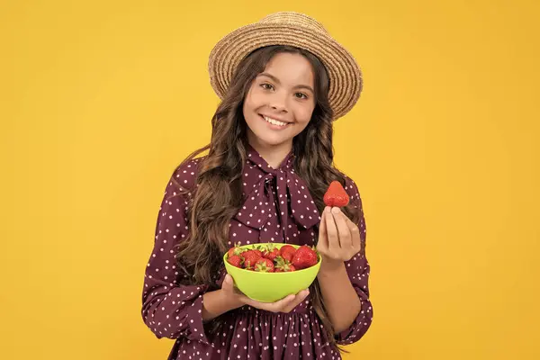 stock image positive teen kid hold strawberry bowl on yellow background.