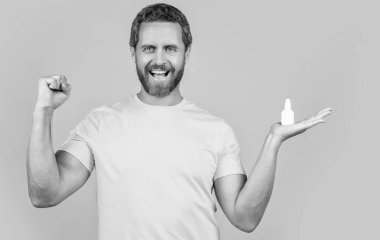 Stüdyoda burun tıbbı yapan mutlu bir adam. Burun tıbbı damlaları olan bir adamın fotoğrafı. Burun tıbbı olan adam sarıda izole edilmiş. Geçmişinde burun tıbbı olan bir adam..