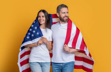 Amerikan bayrağı taşıyan çiftlerin vatanseverliği. Bayrağa sarılı Amerikalı vatansever çifti kutluyoruz. Bayrağı olan Amerikalı bir çift. Bir çift Amerikan bayrağıyla gururla poz veriyor..
