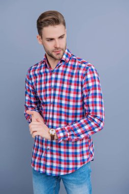 Gri yolda izole edilmiş bir adam. Kareli gömlek giyen milenyum adamı. Milenyum erkeğinin gündelik tarzı. Sıradan bir tişörtle genç bir adamın portresi. Tıraşsız adamın şık bir portresi. Damalı moda.