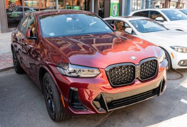 New York City, ABD - 31 Mart 2024: BMW X4 turuncu araba açık havada, köşe manzaralı.