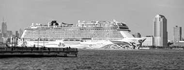 New York, USA - June 13, 2023: Cruise ship Norwegian Joy Sailing next to Manhattan in New York. Skyline of New York Manhattan cruising on the Hudson River cruise liner NCL. clipart