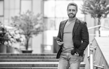 Akıllı telefondan ceketle mesajlaşan adamın fotoğrafı, kopyalama alanı. Adam dışarıda akıllı telefondan mesaj atıyor. Adam sokakta akıllı telefondan mesaj atıyor. Adam dışarıda akıllı telefondan mesaj atıyor..