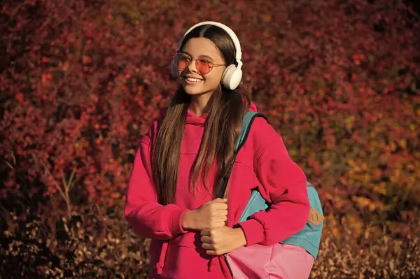 stock image school girl in autumn. student schoolgirl with backpack going to school wearing sunglasses and headphones. back to school. education and knowledge. autumn is a school time. girl from generation z.