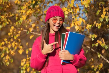 Eylül 'ün 1' inde, Eylül 'de sonbahar doğası. Sonbaharda liseli kız ders çalışıyor. Modern okulda eğitim. Sonbahar stili, okula giden genç bir kız. Bilgi ve eğitim. işaret parmağı.
