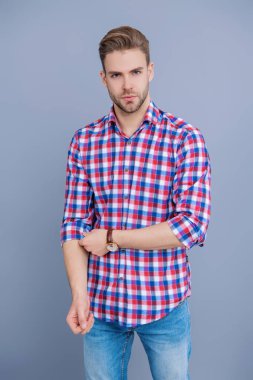 Tıraşsız adamın şık bir portresi. Gri yolda izole edilmiş bir adam. Kareli gömlek giyen milenyum adamı. Milenyum erkeğinin gündelik tarzı. Sıradan bir tişörtle genç bir adamın portresi. Kameraya bakıyorum..