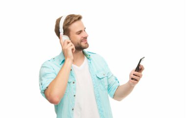 Kulaklıklı adam telefonda mp3 çalma listesini seçiyor. Beyazlar içinde izole edilmiş akıllı telefon uygulaması kullanan adam. Telefonla müzik dinlemek. Müzik yaşam tarzı. Ses çalma listesi. Kulaklıklı adam. Gen z.