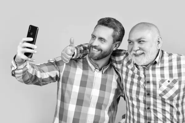 stock image men make family blog in studio, thumb up. men make family blog on background. photo of men make family blog on phone. men make family blog isolated on yellow.