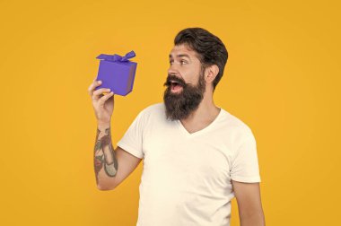 Sarı arka planda izole edilmiş şu anki hâli hayret verici adam. Gömlekli adam için hediye kutusu. Doğum günü çocuğu hediye kutusu tutuyor. Stüdyoda hediye kutusu olan sakallı adam..