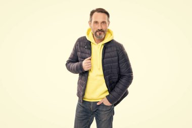 Adam gülümsüyor ve stüdyoda kalın bir ceket giyiyor. Olgun bir adam için sonbahar ceketi. Olgun bir adamın kalın ceketi. Ceketli olgun bir adam beyaz arka planda izole edilmiş..