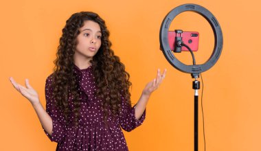 Uzun kıvırcık saçlı hayret bir çocuk blog için video yapıyor..