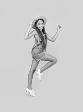 happy teen girl in straw hat running on yellow background.