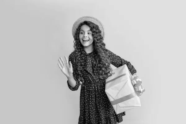 Stock image amazed child with curly hair hold present box on yellow background.