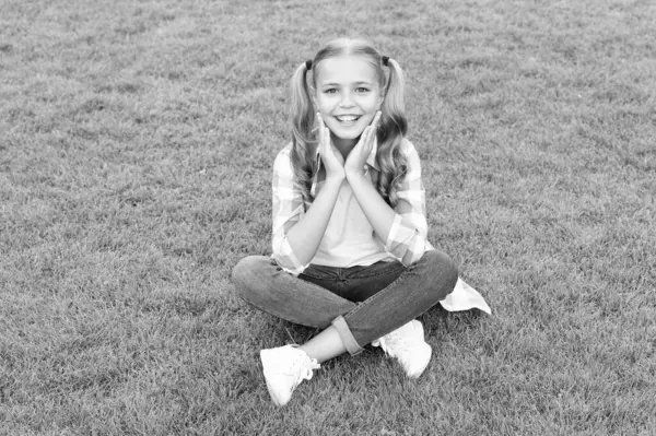 happy teen child sit on green grass outdoor.