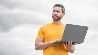 Bilgisayarda çalışan bir adam gökyüzü arka planında. Boşluğu kopyala.