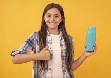 teen girl with shampoo cosmetics isolated on yellow, thumb up. teen girl with shampoo cosmetics in studio. teen girl with shampoo cosmetics on background. photo of teen girl with shampoo cosmetics.