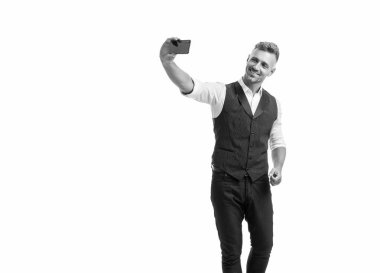 Happy professional guy in suit vest making videochat using smartphone isolated on white.