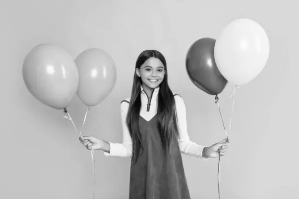 Stock image cheerful child with party colorful balloons on yellow background.