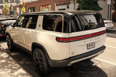 New York, ABD - 06 Ağustos 2023: Rivian R1S beyaz SUV arka ve sürücü tarafı manzaralı, park edilmiş.