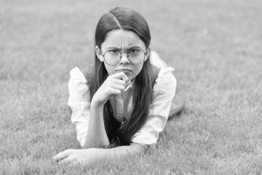 School and education. Frown teen girl in glasses lying on grass after school. back to school.