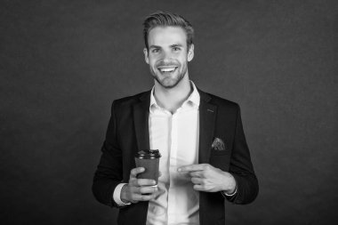 Siyah arka planda kahve fincanı olan mutlu bir iş adamı..