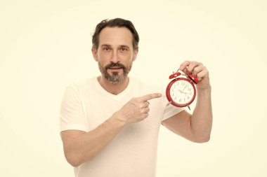 man with alarm clock in studio, point finger. man with alarm clock on background. photo of man with alarm clock. man with alarm clock isolated on white.