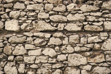 Duvarın arkasında taş duvar var. Taş duvar ustası, gri duvar arkaplanı. Arka plandaki taş duvar gri renkte. Taş duvar ustası, gri duvar arkaplan dokusu.