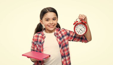 school girl hold alarm clock on background. photo of school girl with alarm clock and homework. school girl with alarm clock isolated on white. school girl with alarm clock in studio.