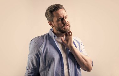 Stüdyoda kaşınan bir adam var. Kaşındıran bir adamın fotoğrafı. Kaşındıran bir adam. Acı çeken bir adam gri arka planda izole edilmiş..