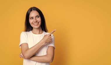 Fotokopi alanını işaret eden sıradan bir kadın. Sıradan giyinen bir kadının fotoğrafı. Sarı arka planda izole edilmiş günlük gömlekli bir kadın. Stüdyoda sıradan bir kadın..