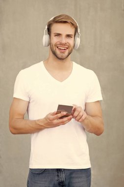 Neşeli adam mp3 müzik listesini beyaz gömlekle seçiyor. İnsan mp3 müzik listesinin kulaklıkla fotoğrafı. Adam mp3 müzik listesini açıyor. Adam dışarıda mp3 müzik listesi kullanıyor.