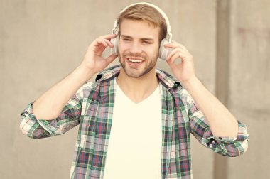 cheerful man listening music outdoor. man listening music outside. man listening music and wearing checkered shirt. photo of man listening music in headphones.