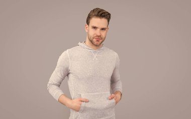 Erkek stüdyosu. Sıradan eşofmanlı yakışıklı bir adam. Beyaz bir adam. Genç adam gri arka plan.