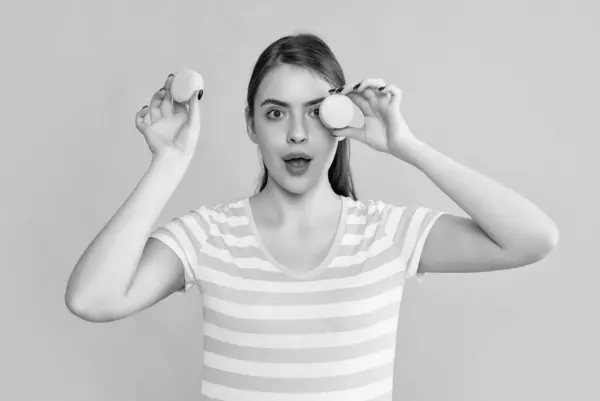 stock image shocked young girl with macaron on yellow background.