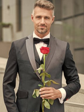 Siyah smokinli zarif adam. Smokin giymiş, papyonlu bir adam. Kırmızı güllü neşeli smokinli adam..