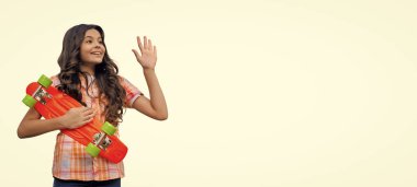 Yaz kaykay aktivitesi. Kaykaycı kız kaykay parkında. Kaykaylı genç kız. Boş zaman konsepti. Kaykaylı şık bir kız beyazın üstünde tek başına selam veriyor. Çocukluk yaşam tarzı. kaykay tahtası.