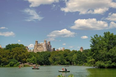 New York, ABD - 22 Temmuz 2023: New York 'ta Manhattan' ın göl ve bina manzaralı Central Park. Teknedeki insanlar.
