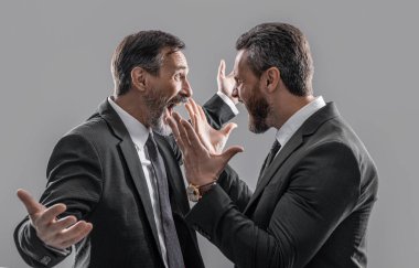 Saldırganlıkla tartışan iş adamlarının fotoğrafı. Gri arka planda iki münakaşa eden iş adamı. Stüdyoda tartışan iş adamları. Tartışan işadamları bağırıyor.