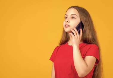 Çocuk sarı arka planda akıllı telefondan konuşuyor..