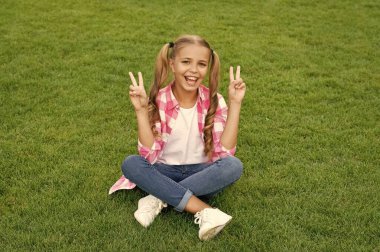 happy teen child sit on green grass outdoor. peace.