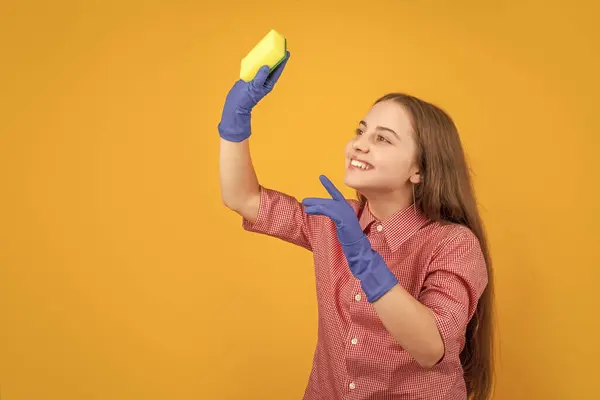 stock image positive child in rubber gloves with sponge on yellow background.