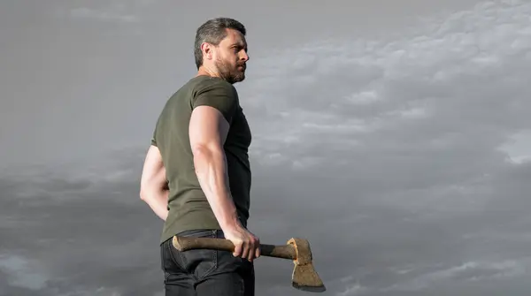 stock image man with axe. lumberman man hold ax. brutal man on sky background.