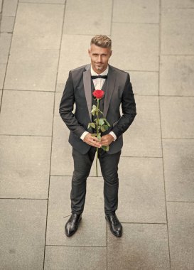 Smokinli şık bir adam. Dışarıda papyon giyen bir adam. Kırmızı güllü karizmatik smokin giyen adam..