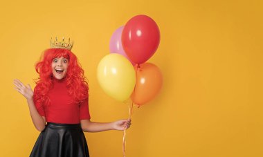 Sarı arka planda helyum balonu olan tacın içindeki mutlu çocuk. Vay..