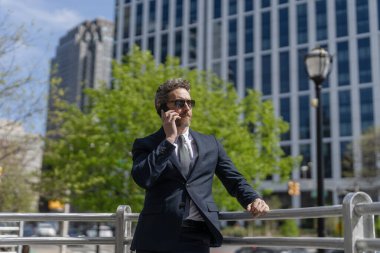 Telefon kullanan bir iş adamı. Takım elbiseli bir adam telefonda konuşuyor. Telefonu olan orta yaşlı İspanyol işadamı. İş iletişimi. İş adamının dışarıyı araması gerekiyor. İletişim stratejisi.